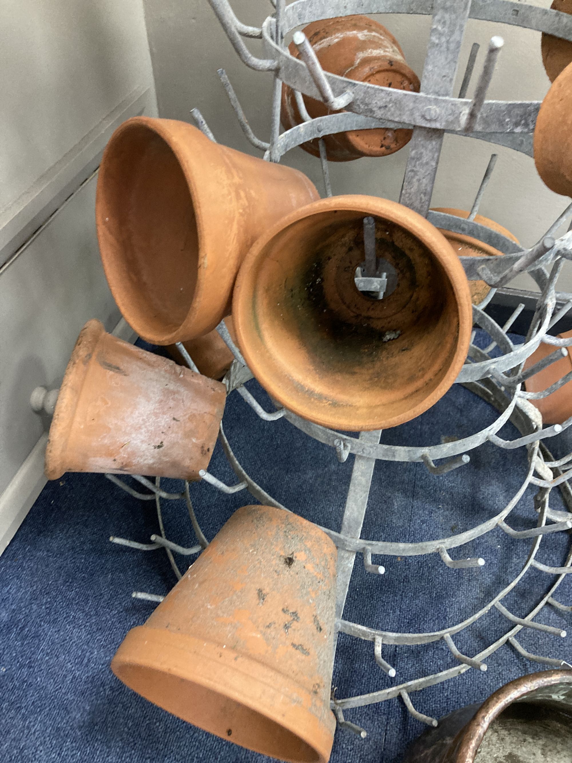 A French metal terracotta pot holder, height 102cm with assorted terracotta pots and an Eastern copper pan, height 21cm